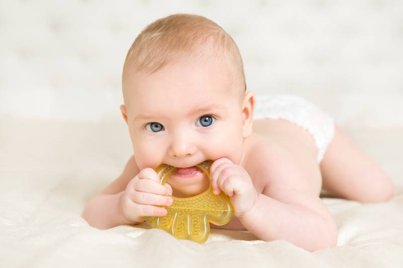 bambino con gioco in bocca