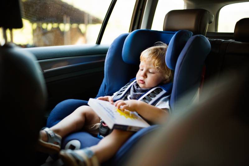 bambino con libro nel seggiolino