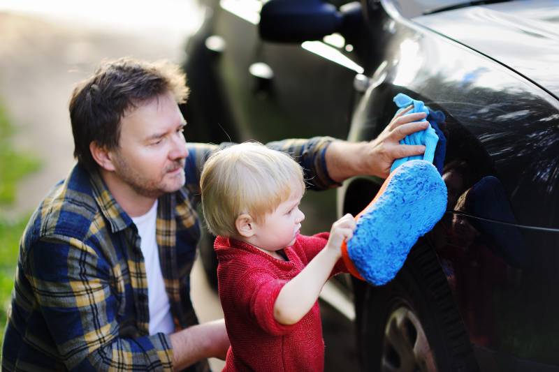 papà e bambino che puliscono l'auto