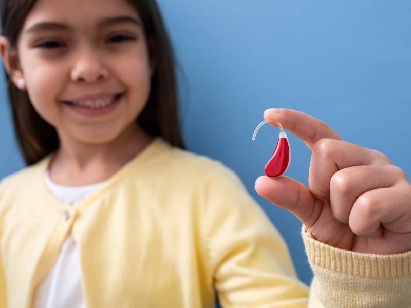 Bambina mostra apparecchio acustico